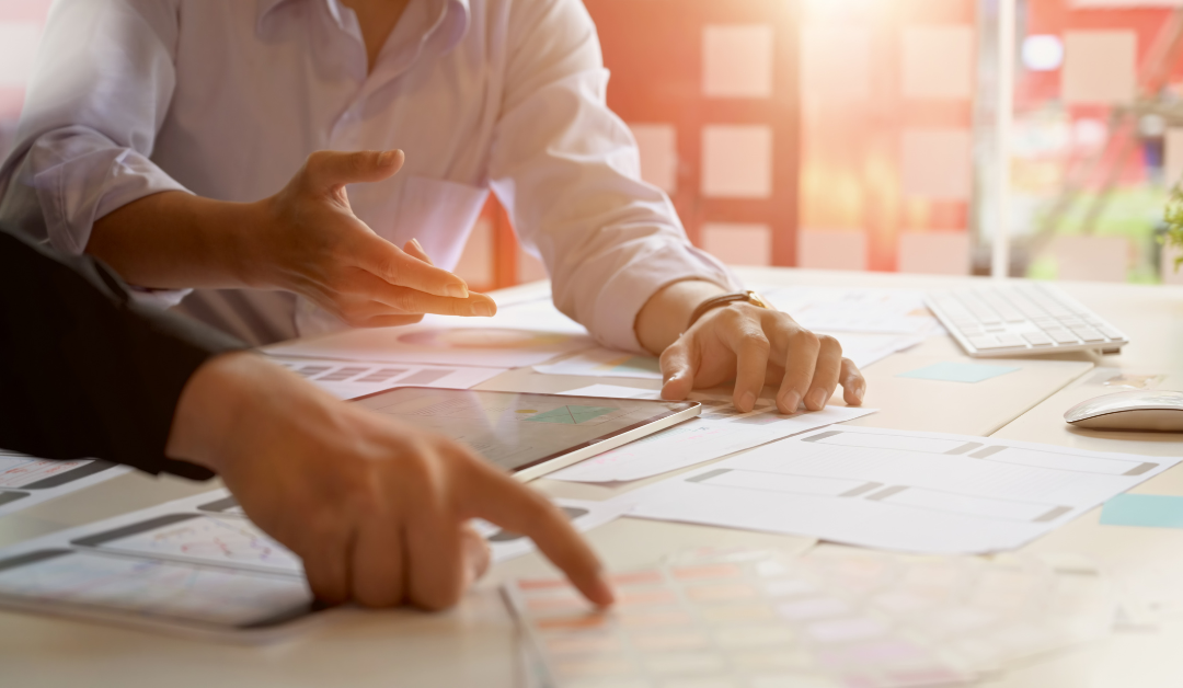 A strategy session with two people and paperwork at a desk.