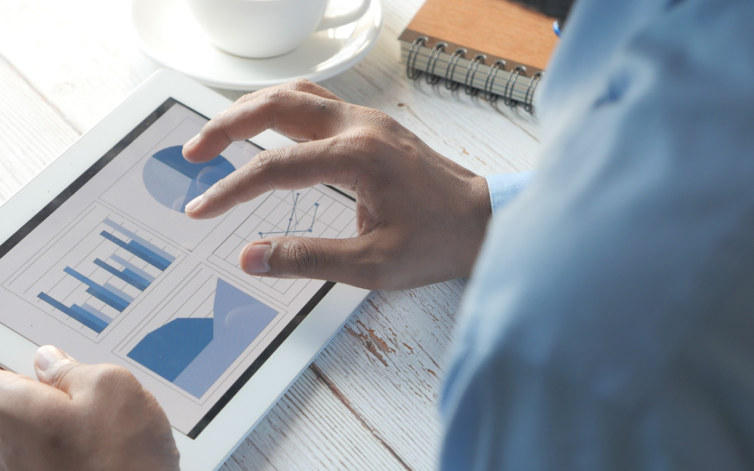 man at desk in business attire holding a tablet with graphs displayed to illustrate the venture capital cycle