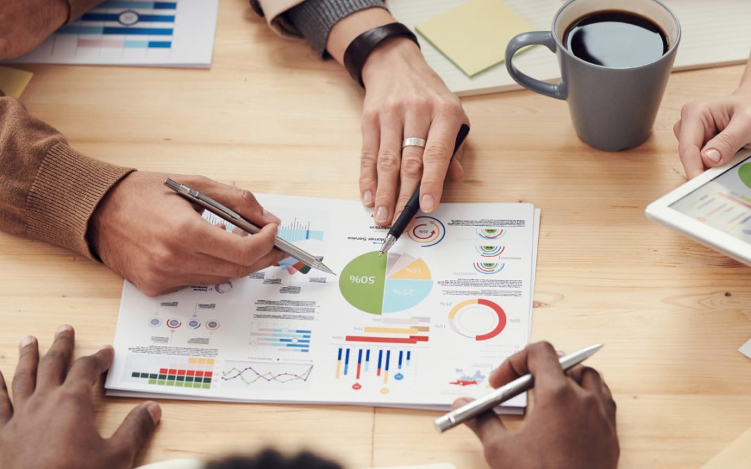 A work table showing graphs and people's hands in the frame to represent effective competitive strategy for startups.