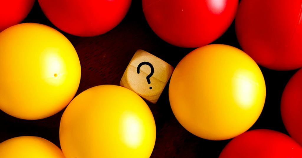 a tile with a question mark amongst red and yellow game balls to represent the four questions to ask yourself before building your startup team. 